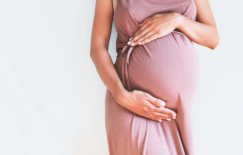 Pregnant woman in dress holds hands on belly-mg-blog