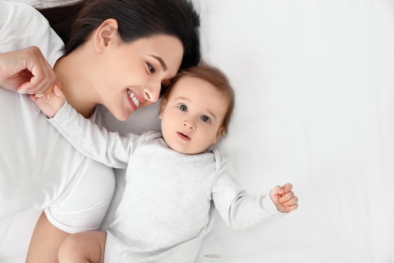 Woman lying next to her baby on the bed